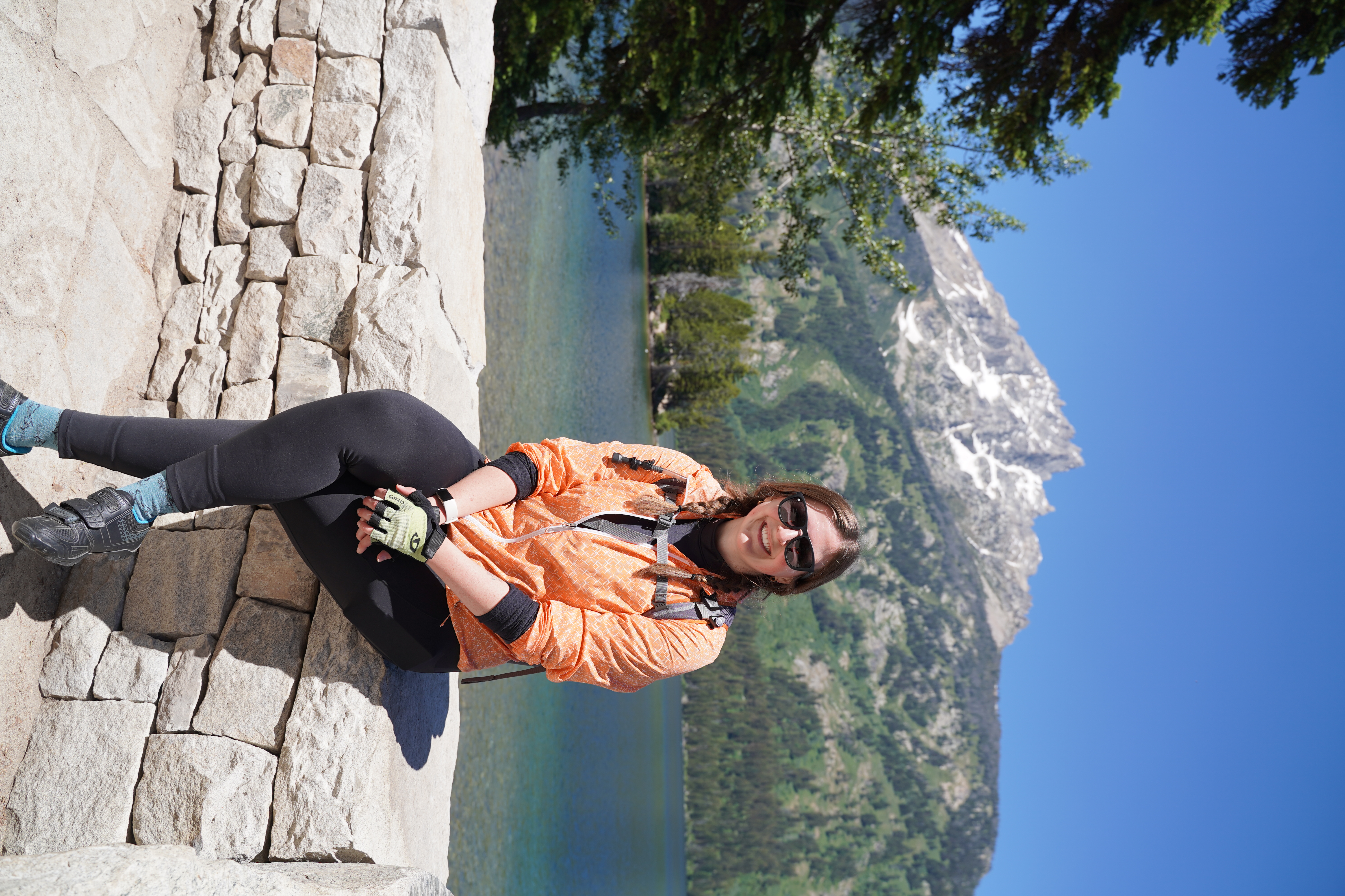 Aubrey Haskett, sitting on a stone wall above an alpine lake